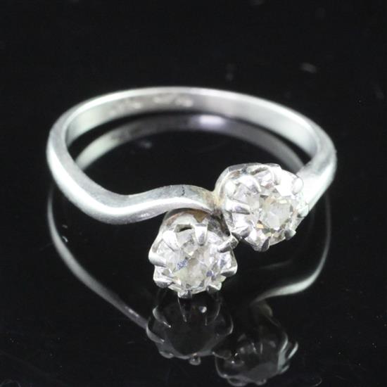 A mid 20th century platinum and two stone diamond crossover ring, size P.